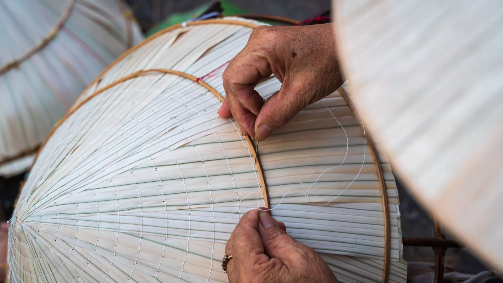 Les mains de l'artisan brodent méticuleusement des chapeaux coniques