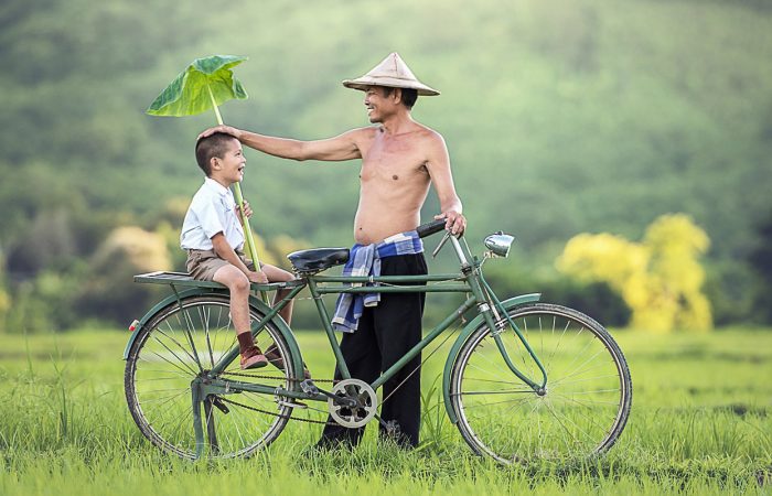 père et son fils à vélo dans la campagne, Cambodge