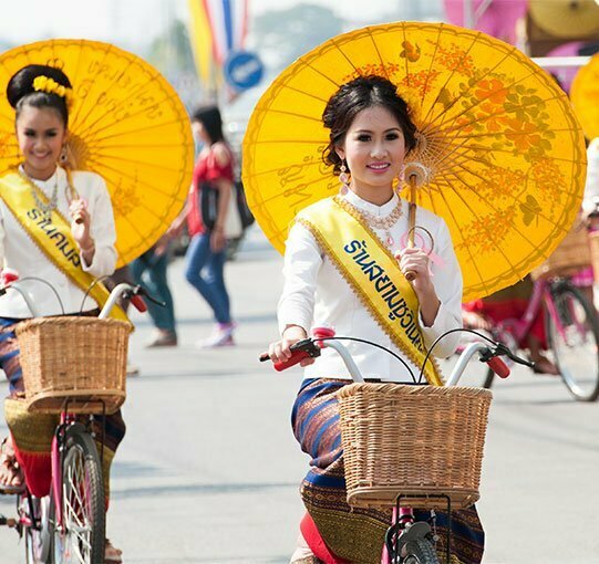 Femmes thaïlandaises sur vélos tenant des ombrelles